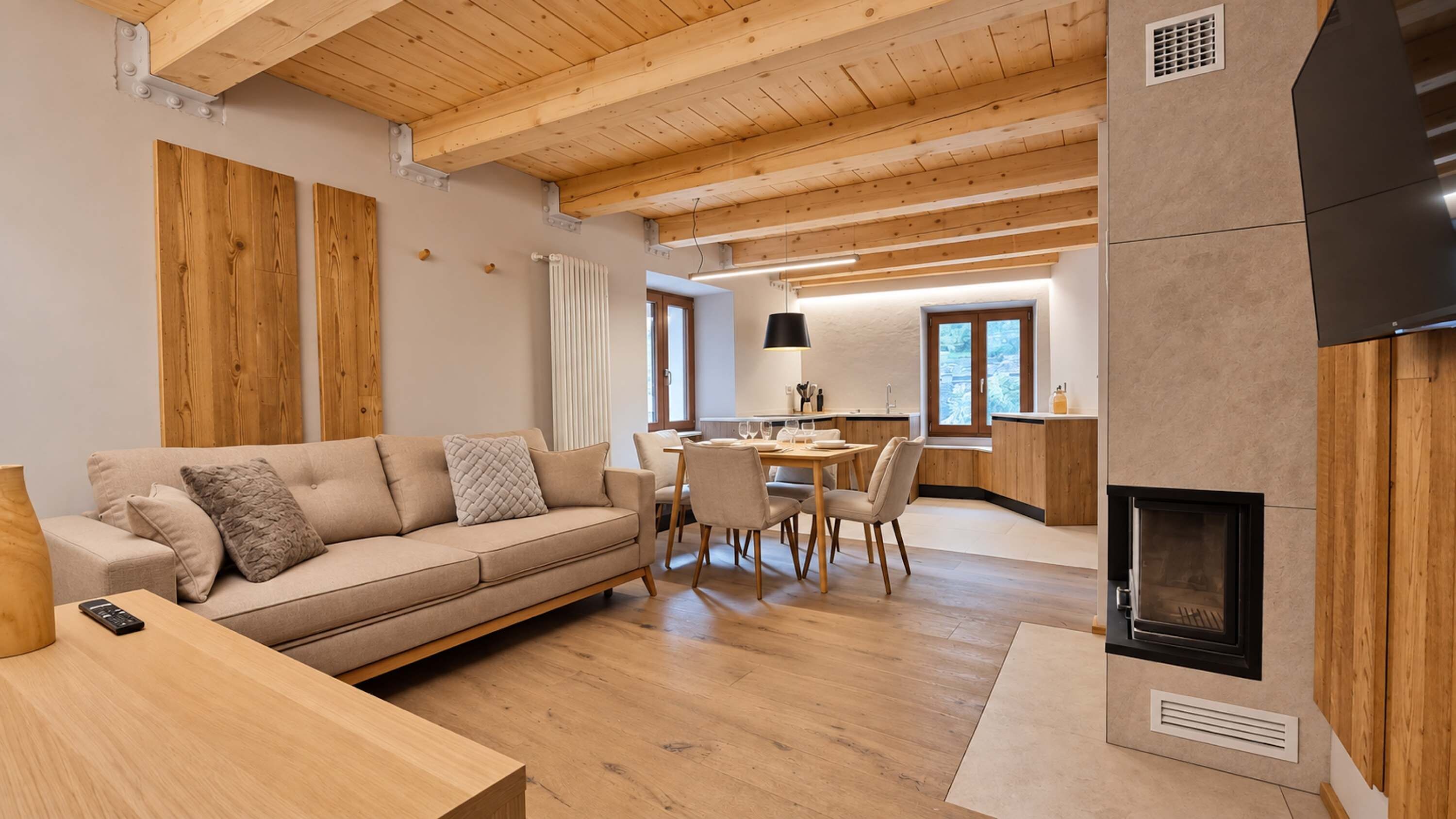 Ein modernes Wohnzimmer mit Holzboden, einer Couch, einem Esstisch und einem Kamin.