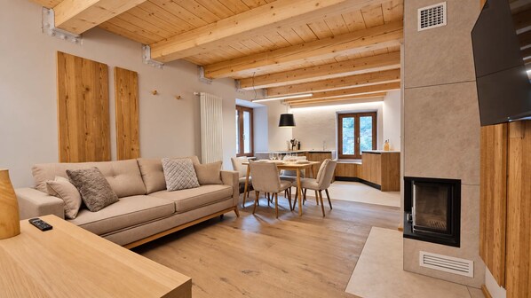 A modern living room with a wooden ceiling, a sofa, a dining table, and a fireplace.