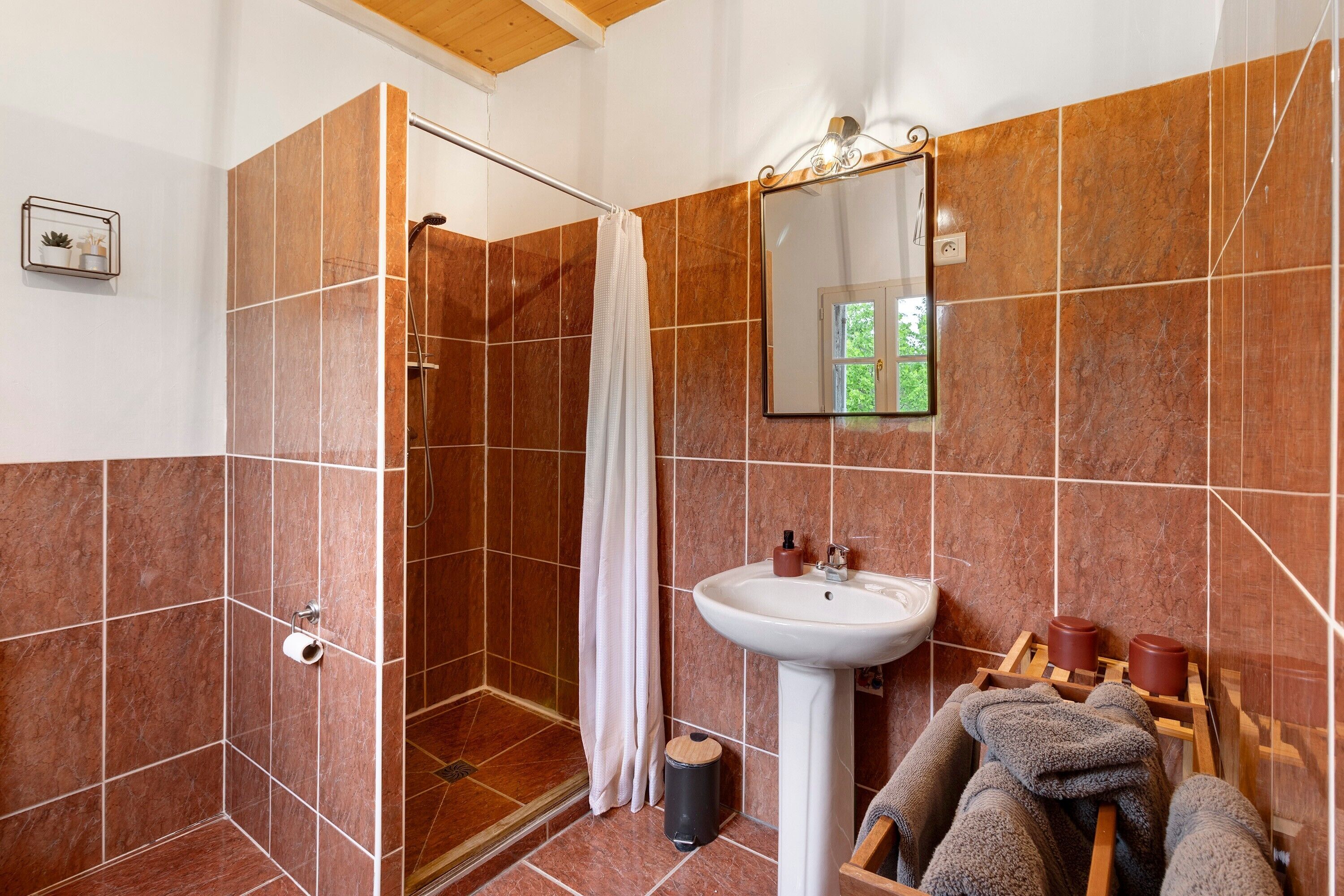 Een badkamer met een douche, een wastafel en een spiegel.