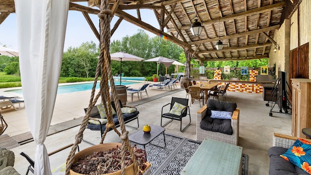 A covered outdoor area with a pool, lounge chairs, and a bar area.