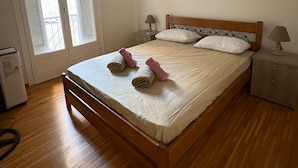 Un dormitorio con una cama de madera, dos lámparas de noche, una mesita de noche y una ventana con contraventanas.