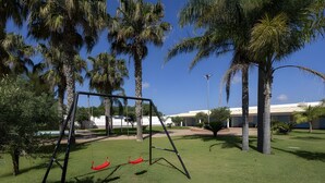 Zona verde con un columpio y palmeras.