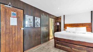 A bedroom with a wooden bed, a sliding door, and a wall-mounted TV. - Grafton Copper | By My Getaways (Brighton)