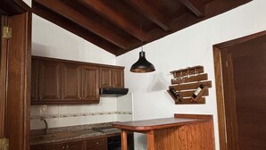 A kitchen with wooden cabinets, a countertop, a hanging light fixture, and a wine rack.