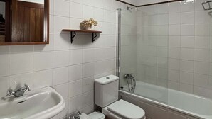 A bathroom with a sink, bidet, toilet, and a glass-enclosed shower.