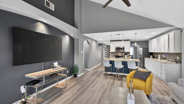 A modern kitchen with white cabinets, a central island, and bar stools.