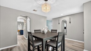 A dining area with a rectangular table, four chairs, and a chandelier.