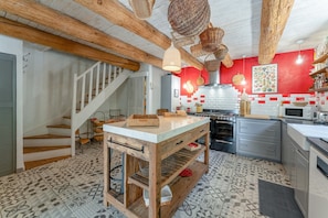 A kitchen with a wooden table, white cabinets, and a red accent wall.