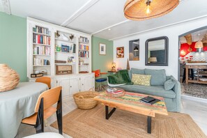 Un salon comprenant un canapé, une table basse, une bibliothèque et un coin repas avec des chaises et une table.