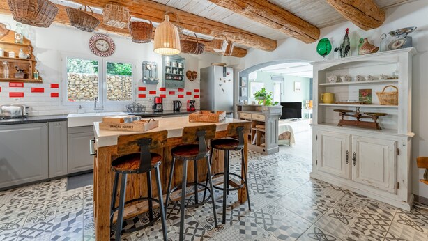 Eine rustikale Küche mit Holzbalken, einer Landhausbarschrank und fliesenbelagtem Boden mit Muster.