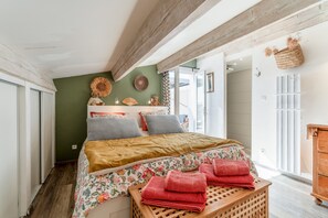 A bed with floral bedding, a wooden headboard, and a basket on the wall.
