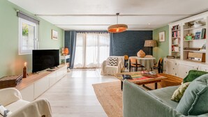 Ein Wohnzimmer mit Fernseher, Sofa, Couchtisch und Bücherregal.