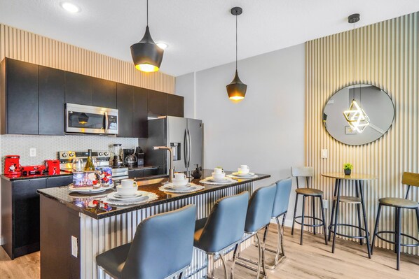 A modern kitchen with a central island, bar stools, and a round table with chairs.