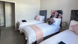 Une chambre d’hôtel avec deux lits, une armoire et une petite table avec une lampe.
