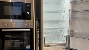 Une cuisine moderne équipée d’un four encastré, d’un four à micro-ondes et d’un réfrigérateur à plusieurs étagères.
