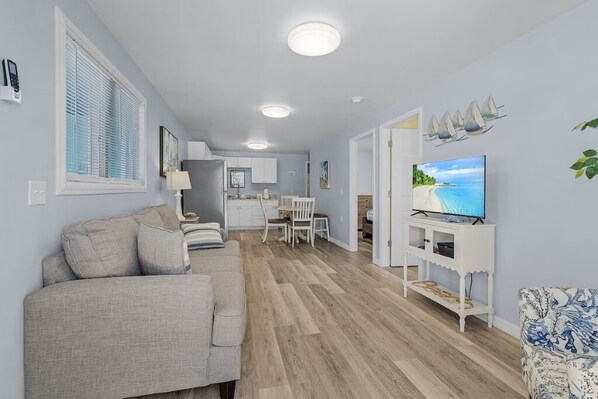 Una sala de estar moderna con un sofá, televisor y zona de comedor.
