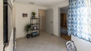 A room with a tiled floor, a door, a shelf with plants, and a patterned curtain. - Apartment 'Topas' with Wi-Fi (Freiburg im Breisgau)