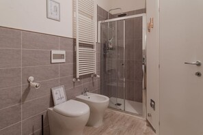 Une salle de bain moderne équipée de toilettes, d’un bidet et d’une douche à parois de verre.