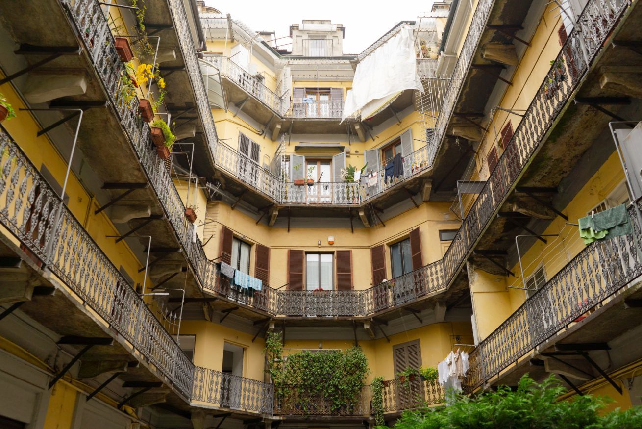 A multi-story building with balconies, some with plants and laundry.