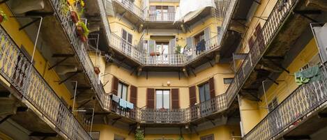 A multi-story building with balconies, some with plants and laundry.
