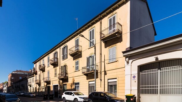 Une rangée de bâtiments traditionnels dotés de balcons, un ciel bleu azur et des voitures garées.