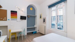 Une chambre à coucher avec un lit, un bureau, des chaises, une télévision et une fenêtre donnant sur un beau paysage.