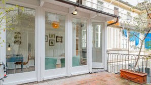 Un pis modern amb grans portes de vidre, un paviment de maó i un petit balcó amb una planta en test.