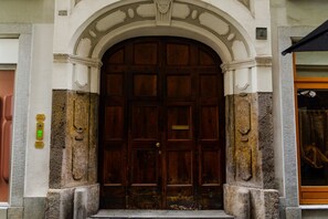 A large wooden door with a brass handle, set within a stone archway. - Palatium by HappyHosTorino (Torino)