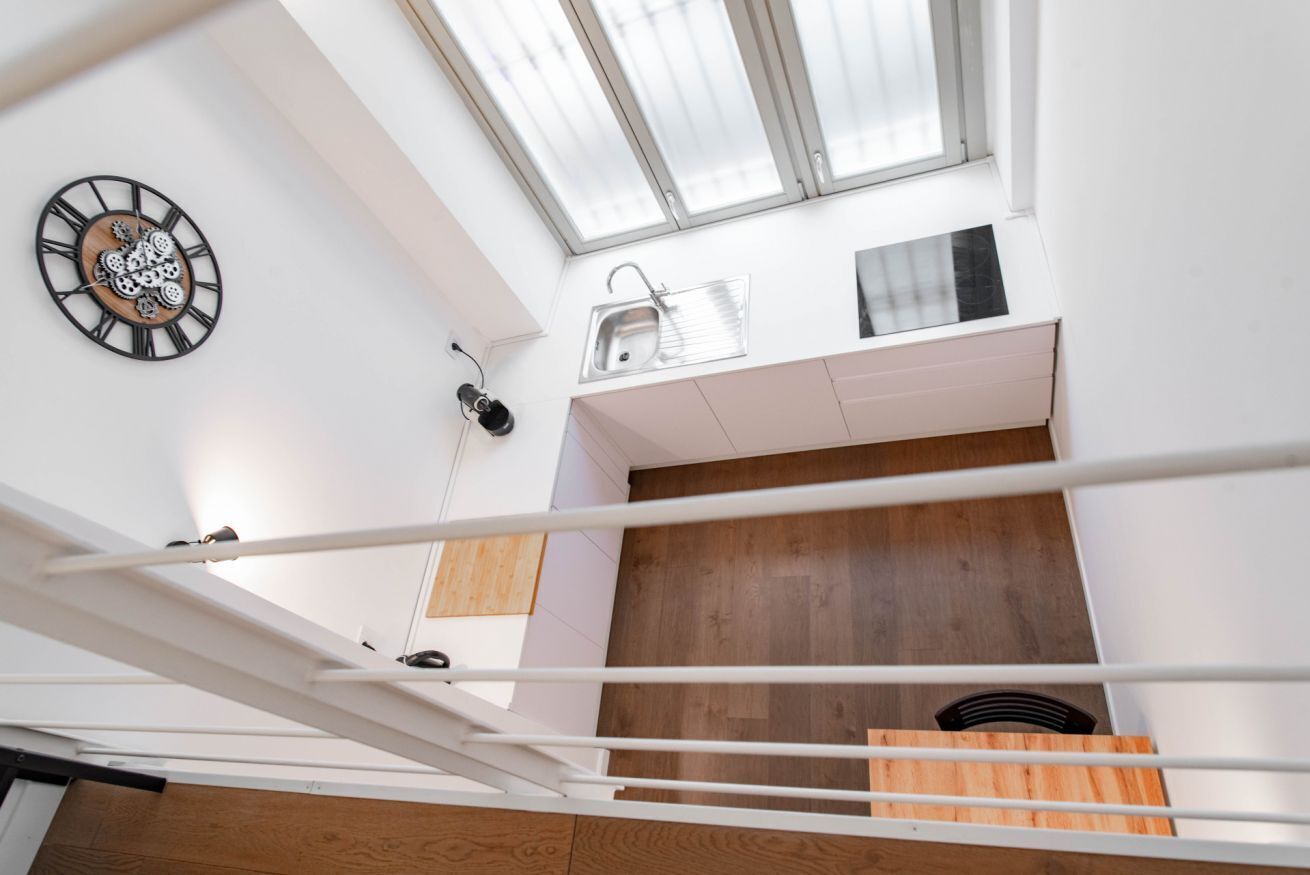 A modern interior with a skylight, a clock, a sink, and a wooden panel wall.