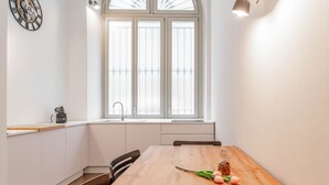 A modern kitchen with a wooden table, a window with blinds, and a clock on the wall. - [Centro]: Dream Loft by HappyHosTorino (Torino)