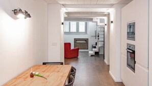 A modern kitchen with white cabinets, a built-in oven, and a dining area with a wooden table and chairs. - [Centro]: Dream Loft by HappyHosTorino (Torino)