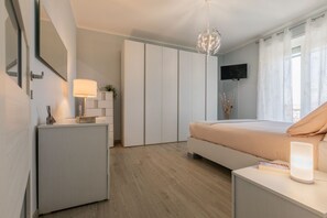 A modern bedroom with a bed, bedside tables, a wardrobe, a TV, and a lamp.