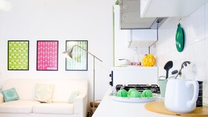 Une cuisine moderne avec un plan de travail blanc, une tasse blanche et une théière verte.