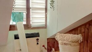A room with a window, a radiator, a white basket with a lace cover, and a wooden cabinet.