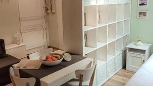 A neatly organized room with a dining table, chairs, a white cabinet, and a shelving unit against the wall.