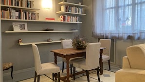 Un comedor con una mesa de madera, cuatro sillas y una estantería llena de libros.