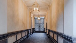 A hallway with a black and white marble floor, a black balustrade, and a large, ornate gate at the end. - Enjoy Torino City Center (Torino)