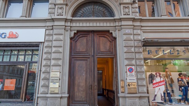 A building with a large wooden double door, a sign for 'BELLIS' on the right, and a 'no parking' sign on the left. - Enjoy Torino City Center (Torino)