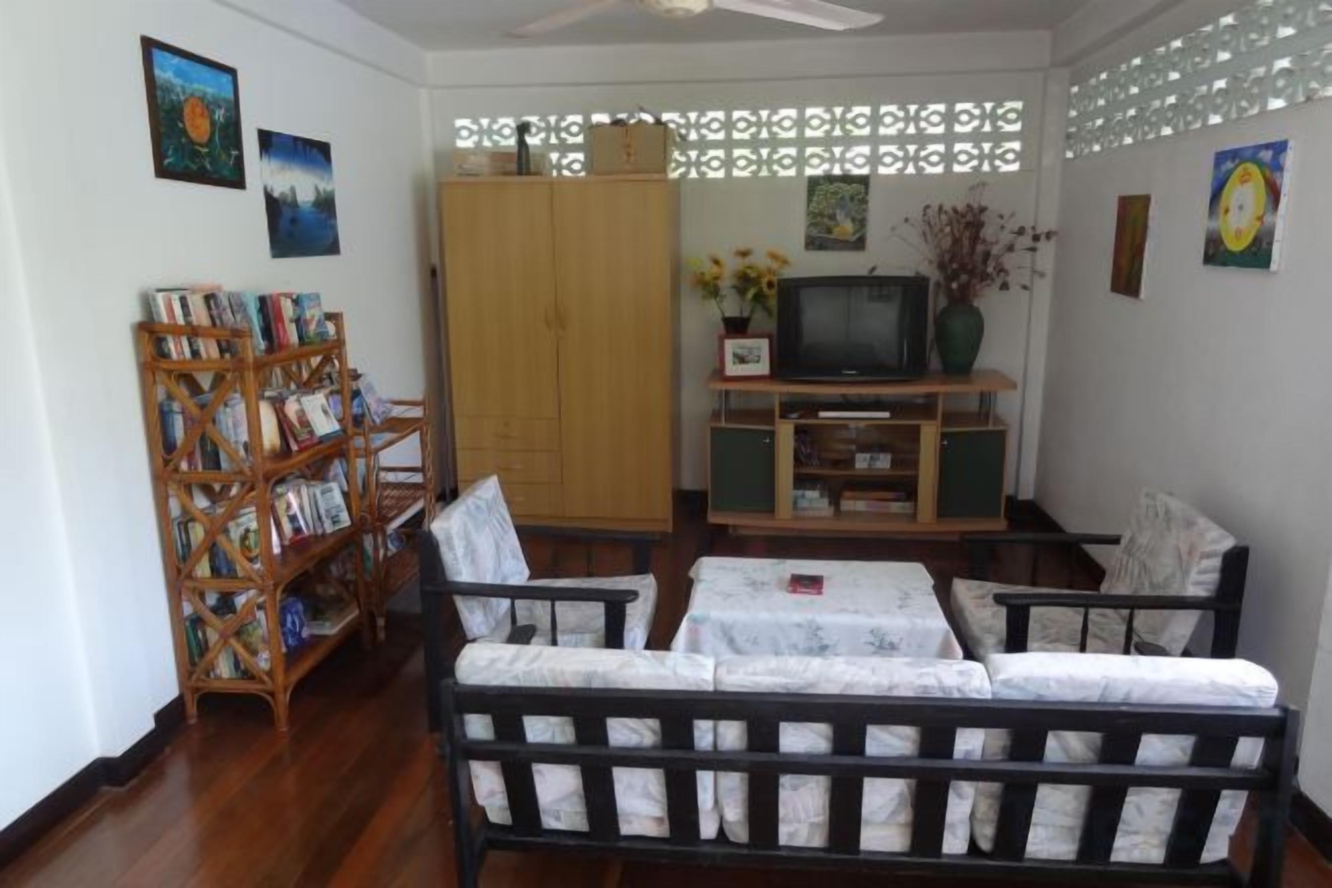Una sala de estar con un sofá, un televisor, una estantería y un biombo decorativo.