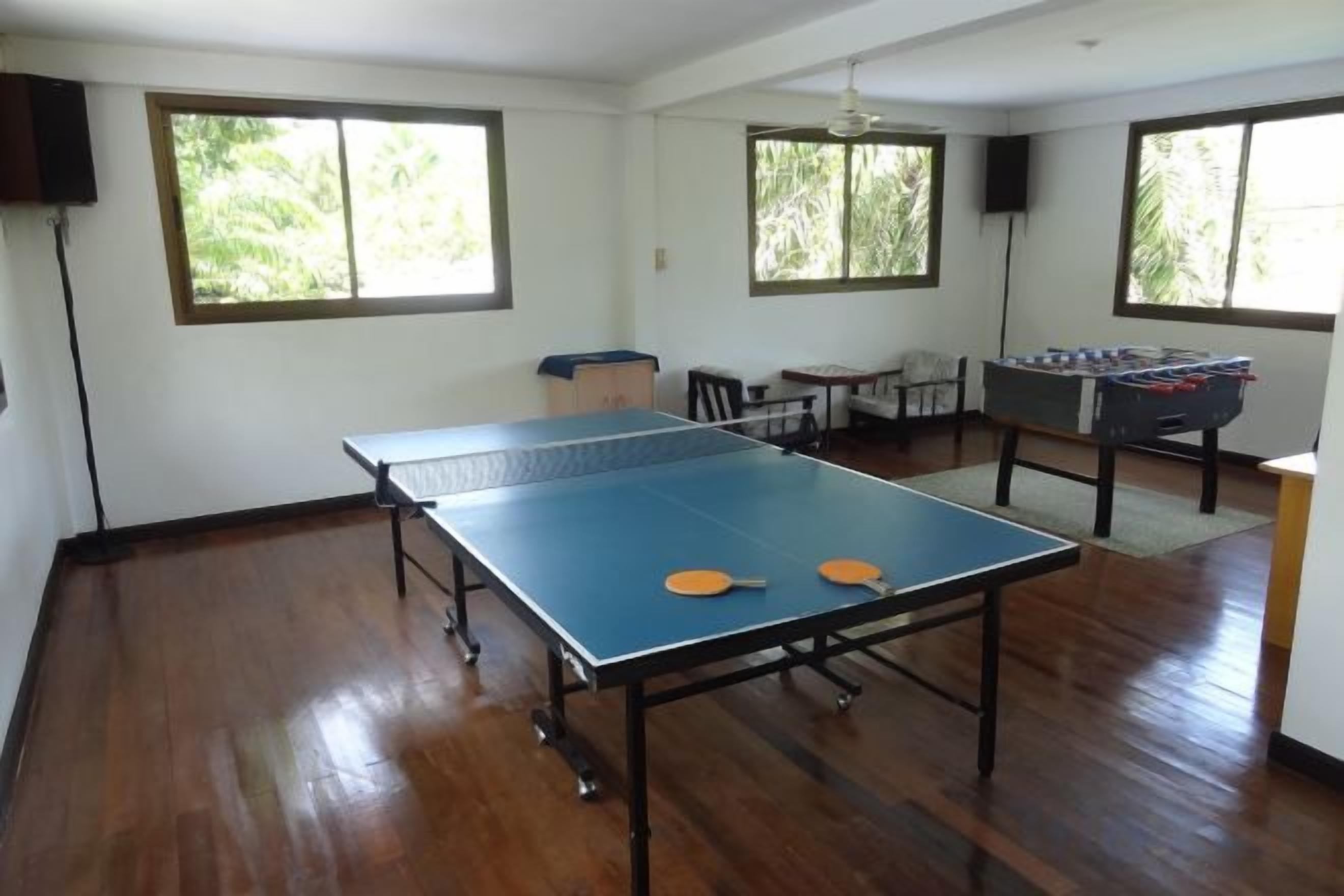 Una habitación con mesa de ping pong, mesa de fútbol y ventana con vistas a zonas verdes.