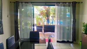 Une pièce dotée d’une porte vitrée donnant sur un espace extérieur aménagé avec des chaises et une table.