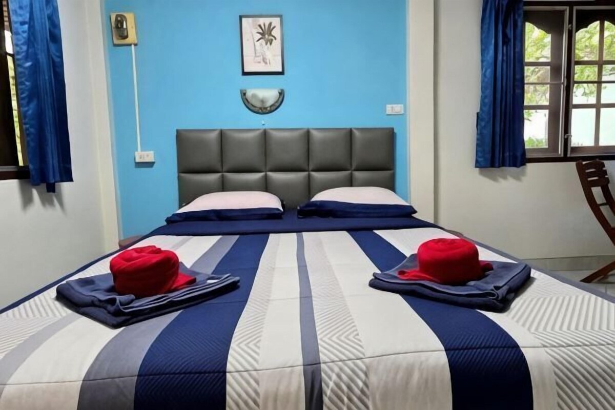 A bed with a striped bedspread, two pillows, and two red hats on the bed.