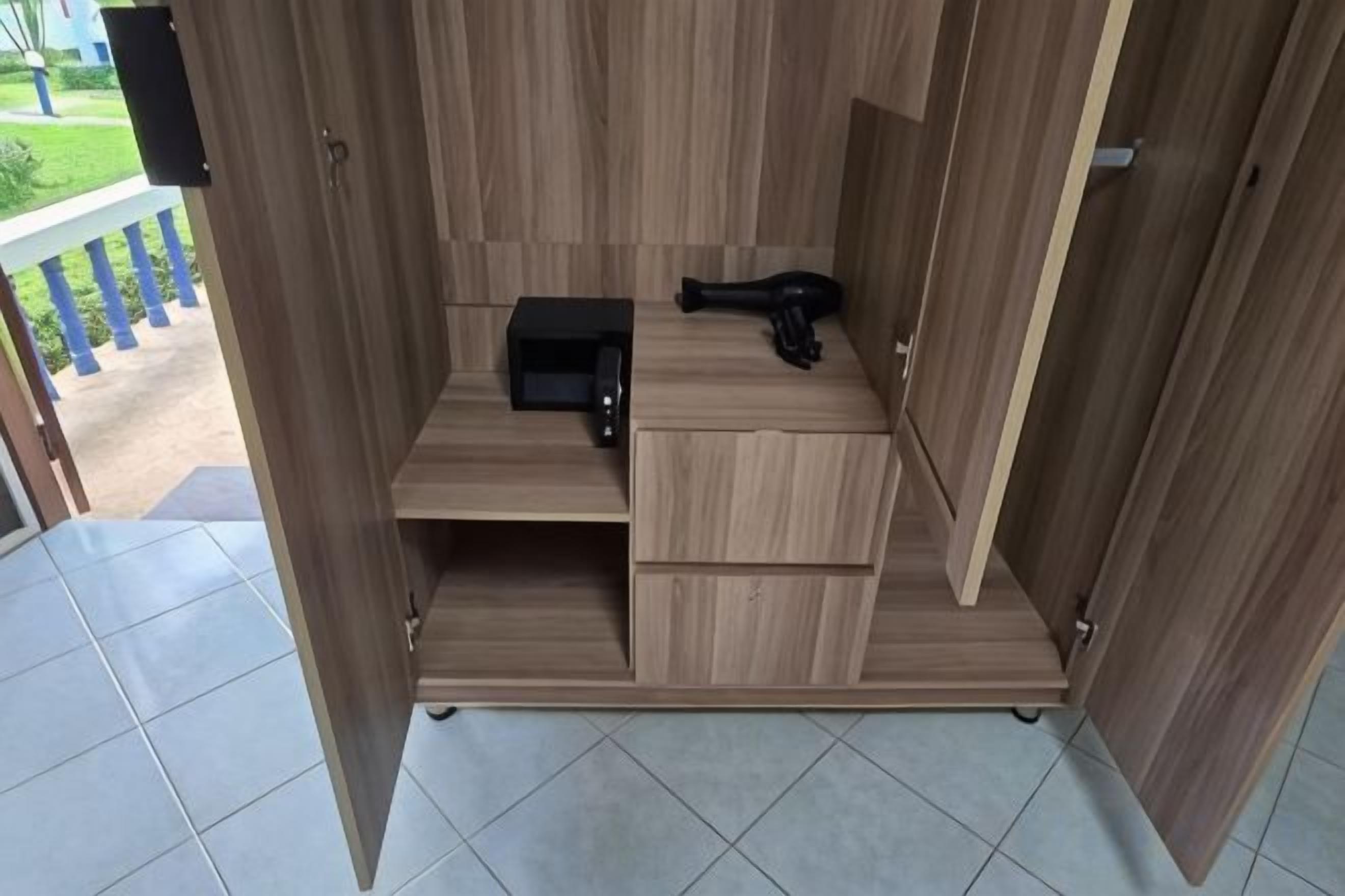 Una habitación compacta de madera con microondas integrado, un pequeño electrodoméstico negro y un armario de almacenamiento.