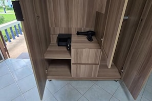 Een compacte houten kamer met een ingebouwde magnetron, een klein zwart apparaat en een opbergkast.