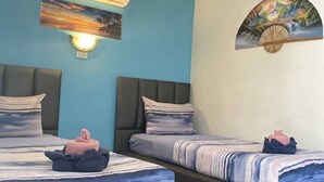 Une chambre d’hôtel avec deux lits, un climatiseur fixé au mur, une lampe fixée au mur et un tableau.