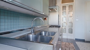 A modern kitchen with stainless steel appliances, a double sink, and a tiled backsplash.