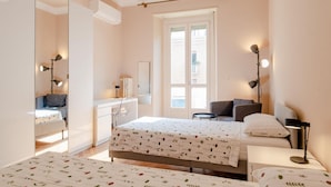 A bedroom with a bed, bedside tables, a desk, a chair, a window, and a mirror.
