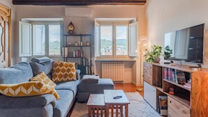 A cozy living room with a sofa, a coffee table, a bookshelf, and a TV. - Casa Mimmo by Happyhostorino (Turin)