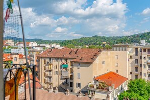 A multi-story building with balconies, a red-tiled roof, and a view of a green hillside. - Casa Mimmo by Happyhostorino (Turin)