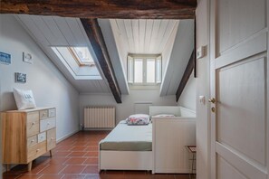 A bedroom with a sloped ceiling, skylight, a bed, a dresser, and a radiator. - Casa Mimmo by Happyhostorino (Turin)